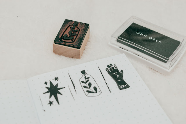 3 used stamps and an ink pad with the stamps printed on a dotted notebook