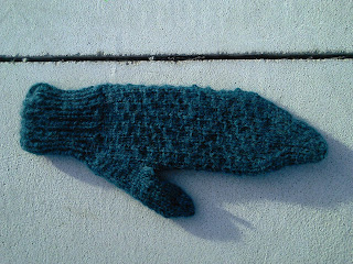 A mitten laying flat, palm-up. There is a slipped-stitch textured pattern along the palm.