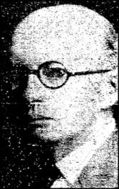 A bald, middle-aged white man wearing round, black-rimmed eyeglasses