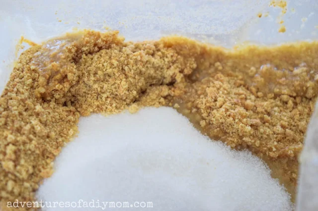 adding sugar and butter to graham cracker crumbs