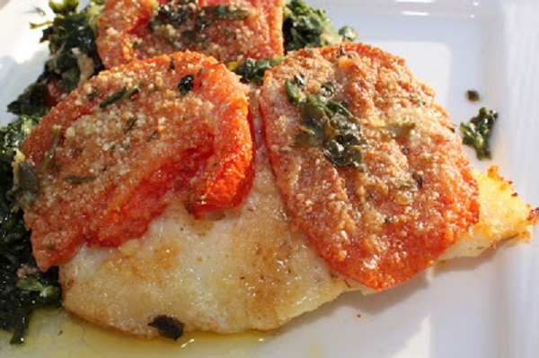baked haddock topped with tomatoes and on a bed of spinach
