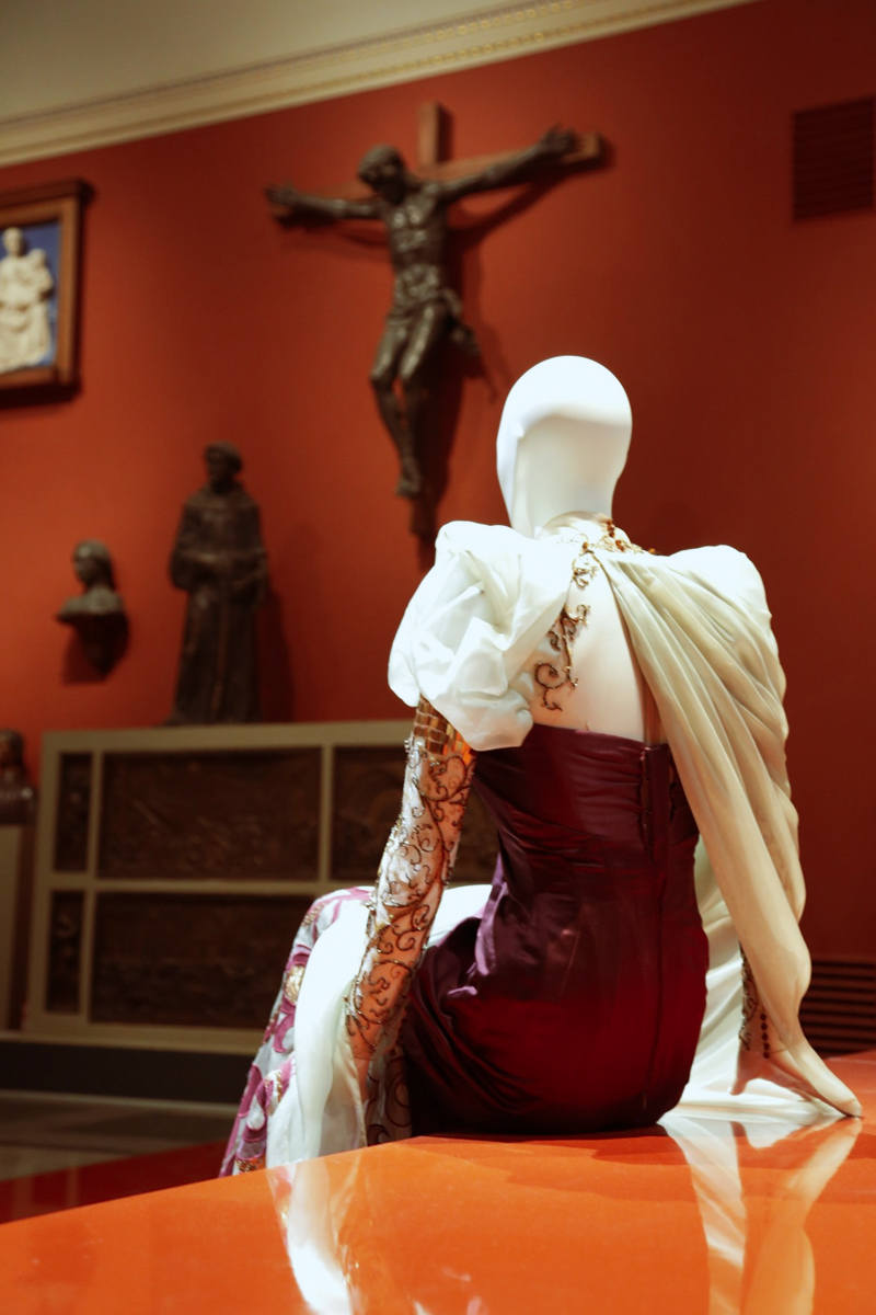 female mannequin in a stunning designer dress in a dark, theater of art surrounded by antique sculptures
