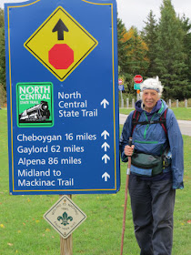 hiker at Midland to Mackinac Trail sign in Mackinaw City