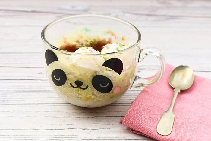 Microwave Jam Sponge Pudding in clear panda mug with pink napkin and small spoon