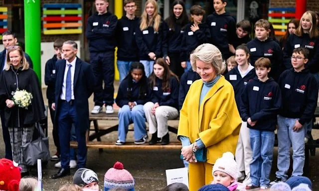 Queen Mathilde wore a yellow wool jacket by Natan. Natan Arrow yellow trousers, and a blue-gray silk blouse