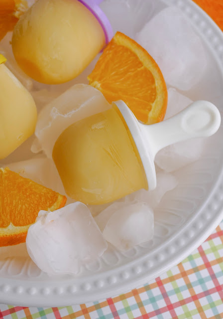 Creamy Orange Popsicle with a white stick in a bowl of ice.