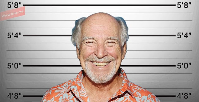 Jimmy Buffett smiling in front of a height chart background