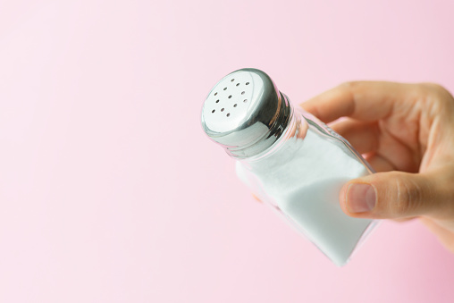 A hand showing white salt in a sprinkler