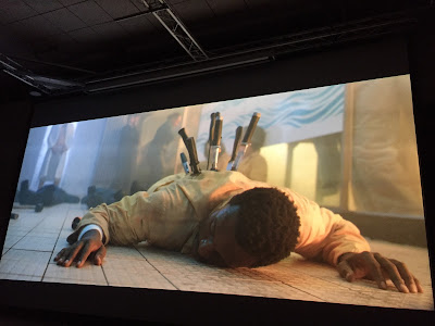 Haapsalu õudukafestival, heltk kinoseansilt. Ekraanil on kollases kombenesoonis meesterahvas kõhuli põrandal, tema seljast turritab välja kümme terariista.