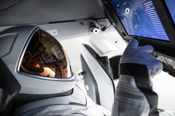 Wearing SpaceX's new EVA suit, Polaris Dawn commander Jared Isaacman works the flight console inside the Crew Dragon capsule.