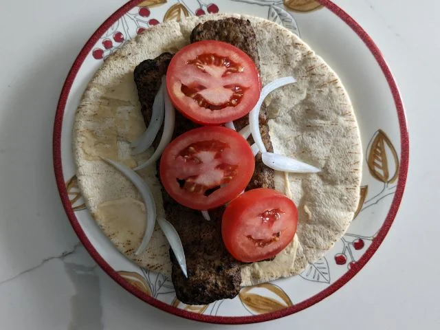 Trader Joe's Middle Eastern Style Kebabs on a pita with hummus, tomato, and onion.