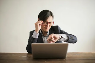 A man looking seriously at a clock, symbolizing the importance of valuing time.