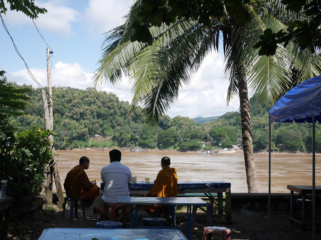 Buddhist monks enjoying early morning iced coffee alongside the river in Luang Prabang, Laos