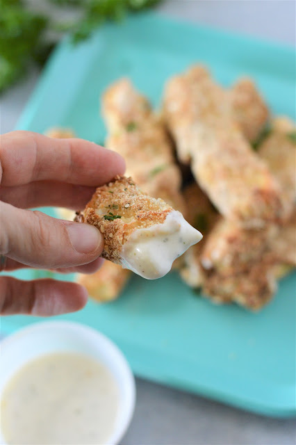 hand holding fish stick with dipping sauce.