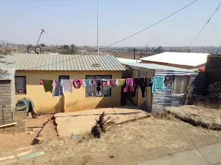 Clothes line of pink, navy blue, light blue, and white clothing hanging in front of a small one story yellow home