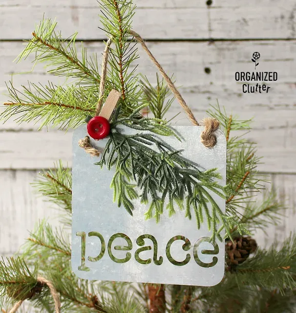 Photo of a galvanized ornament upcycled with a button, clothespin and greenery sprig.