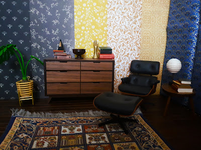 One-twelfth scale modern miniature study with various wallpaper options clipped behind a chest of drawers and Eames armchair.