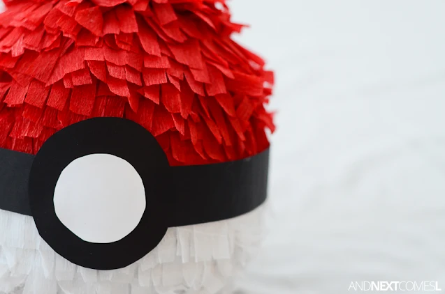 Close up of white crepe paper and red crepe paper streamers on a DIY pokeball pinata