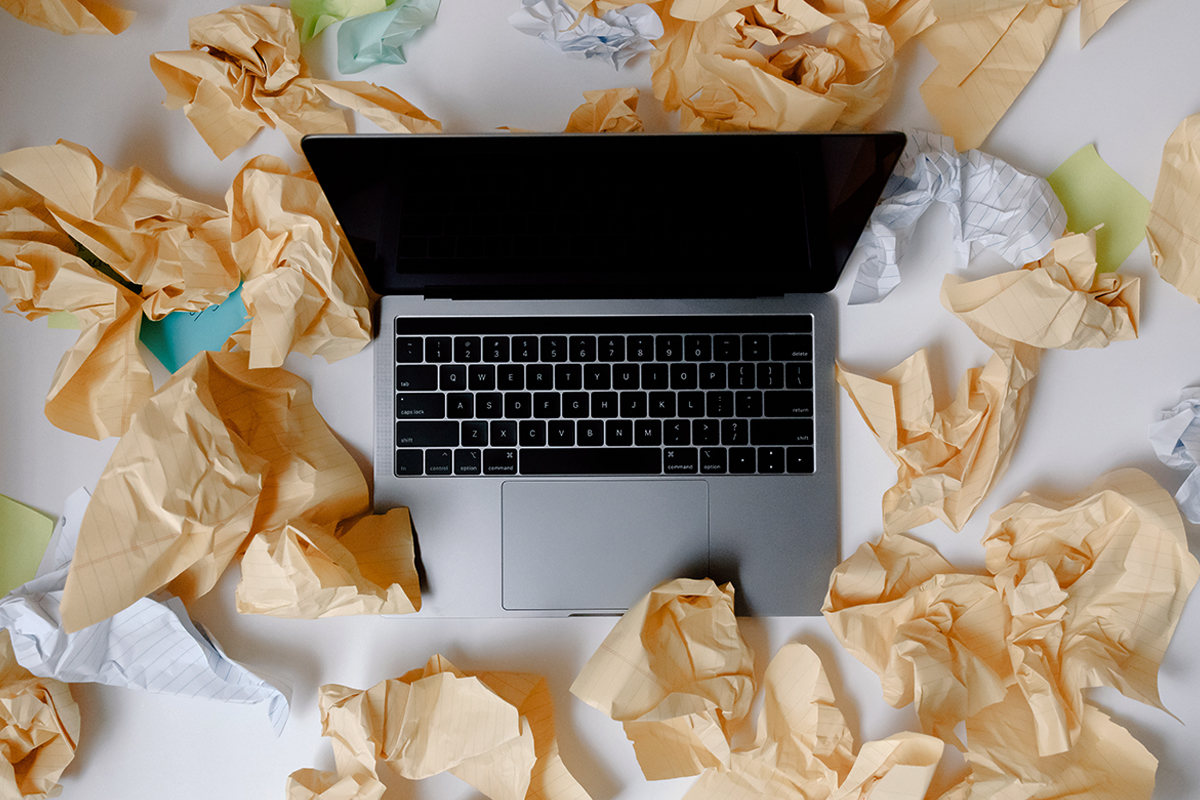 close-up of laptop surrounded by crambled pieces of paper