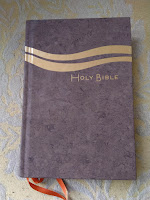 A photo of a brown book with two beige wavy lines on the cover above the words Holy Bible