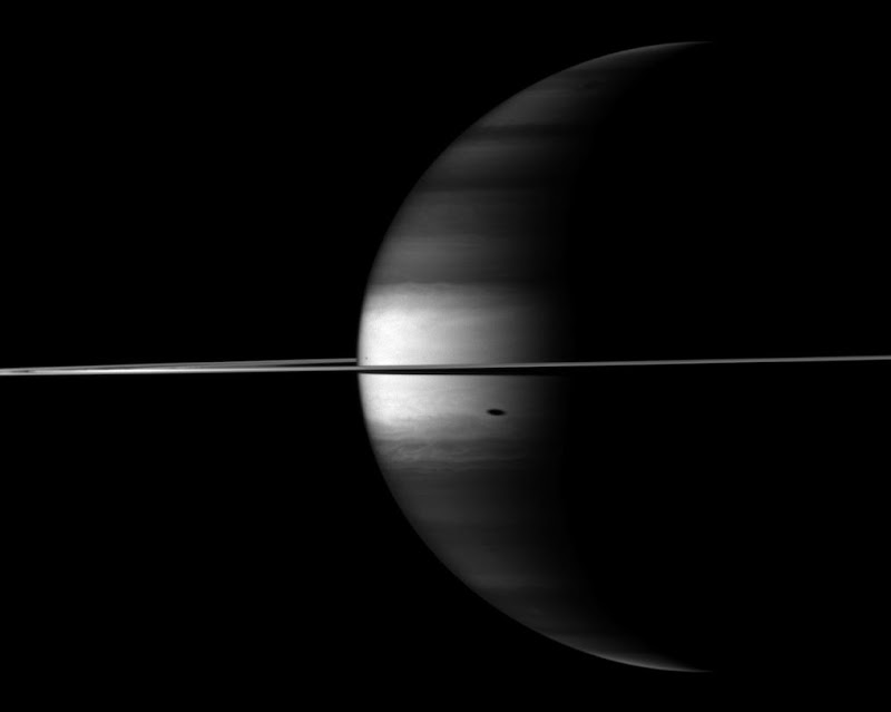 The Cassini spacecraft's camera looks in near-infrared light at a dramatic view of Saturn, its ringplane and the shadows of a couple of its moons.