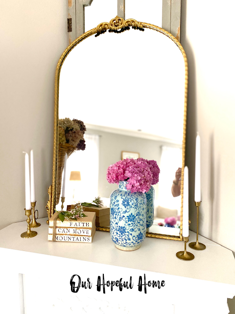 large gold wall mirror brass candlesticks hydrangea vase deconstructed book bundle