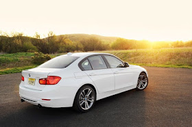 Rear 3/4 view of white BMW 328i parked in country setting