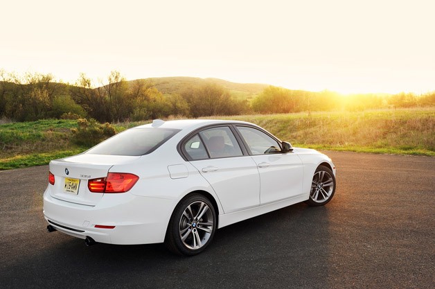 Rear 3/4 view of white BMW 328i parked in country setting