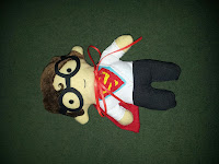 Complete plushie of Clark Kent mid changing into Superman costume with glasses and cape and logo showing through his open shirt