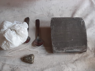 bolsa, cuchara y piedra junto a una placa de arcilla