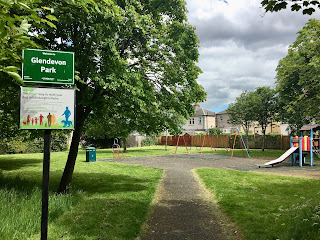 A green sign for Glendevon Park with a playground behind it.