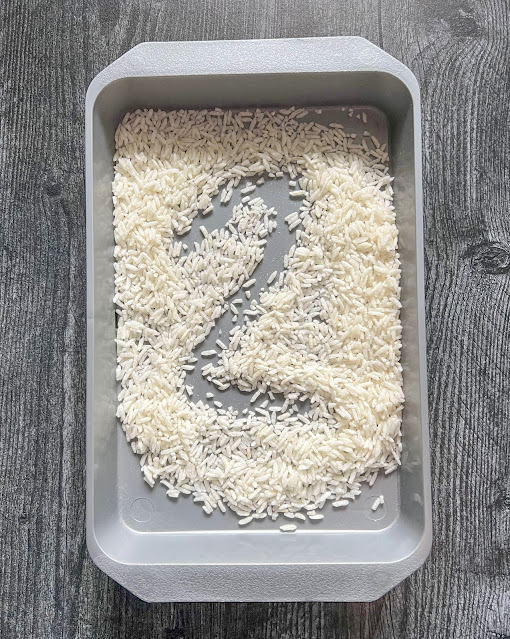 the number 2 written in rice in a gray tray.