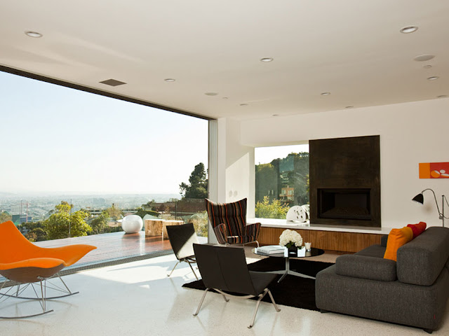 Picture of the living room with black painted fireplace, orange swaying chairs and beautiful city views