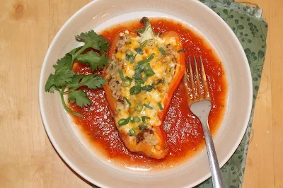 Serving plate with a chorizo and rice stuffed pepper.