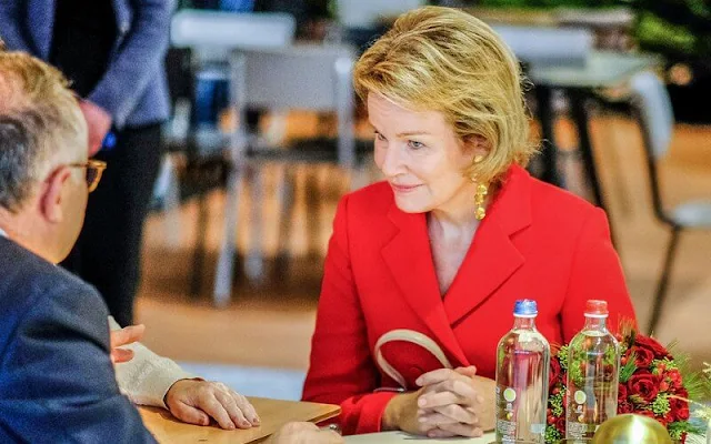 Queen Mathilde wore a red double-breasted blazer by Natan, and red trousers by Natan. Beige fur coat