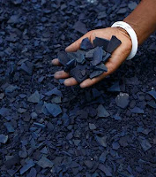 A hand holding indigo dye in a cake-like form.