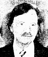 News clipoping photo, poor quality, of a middle-aged white man with a receeding hairline and a mustache, wearing a jacket and tie