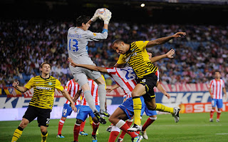 Courtois agarrando un balón en el aire durante un partido, en el cual está rodeado de jugadores.
