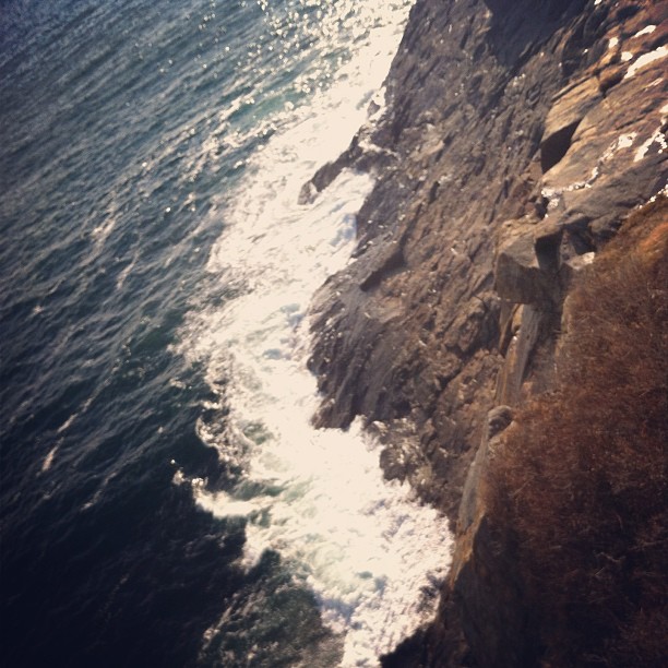 rocky cliffs, ocean cliffs in Maine, new england, foamy waves breaking at the foot of the cliffs, January ocean, cold ocean