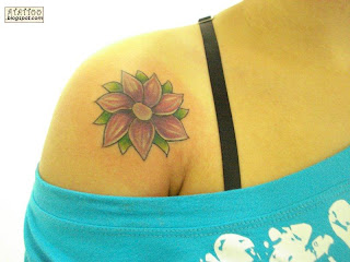 Flor roxa tatuada no ombro.
