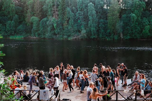 People dancing near a lake with tress on other side