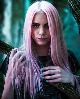 Female with intense stare and pink hair watches you