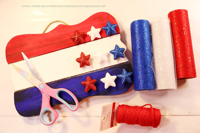 Painted wooden sign with foam stars attached with tulle and scissors nearby on a table