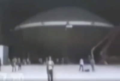 Lots of people stood in hangar and around aircraft hangar watching massive absolutely huge Flying Saucer while it's been moved.