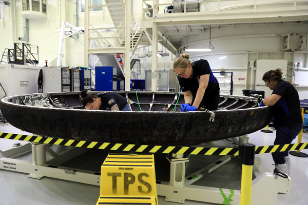 Technicians study the heat shield of the Orion Artemis 1 spacecraft during a post-flight inspection...at NASA's Kennedy Space Center in Florida.