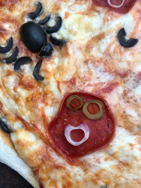 Close up of a monster face on a pizza.