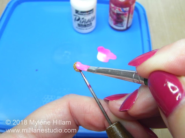 Using the paint brush to paint the alcohol ink petals around the sides of the resin ball.