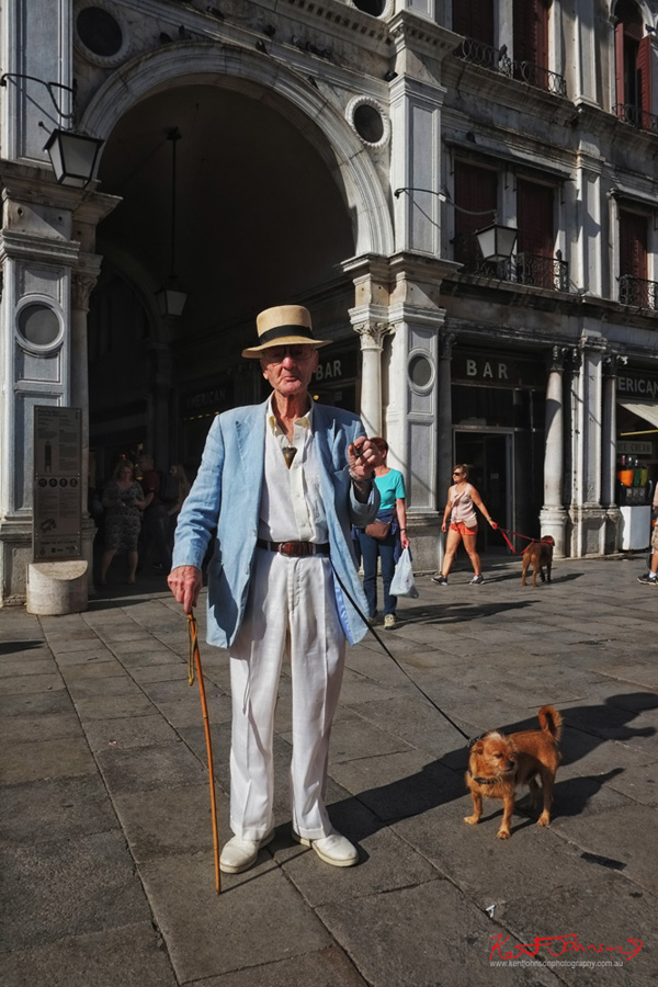 Piazza San Marco, Venice. Classic Italian menswear for summer, panama hat, linen jacket and trousers, a cane, a dog and a cigar. Photographed by Kent Johnson.