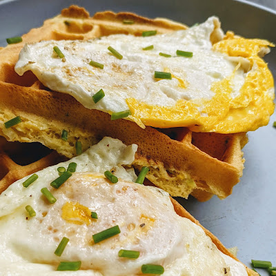 Waffles covered with crispy fried eggs and chives.