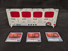 The display stand. Four cards have been slotted into the red cellophane windows, revealing the words 'scream,' 'ink,' 'window,' and 'white.' In front of it are three of the floppy disk cards, turned face up to reveal the number codes '2.3.4,' '3.1.2,' and '4.1.3.'